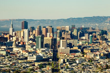 A vibrant cityscape featuring a variety of tall buildings against a clear blue sky.
