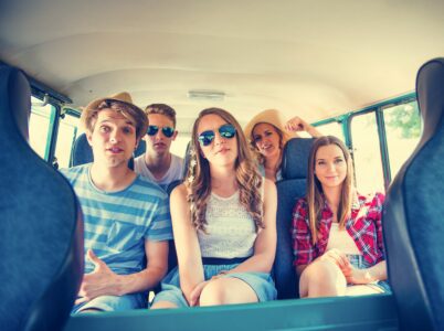Group of friends smiling and chatting inside a car, enjoying a fun outing together.