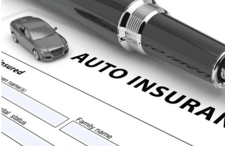 Close-up of an auto insurance form with a pen and a small car model placed on top, symbolizing vehicle coverage and policy documentation