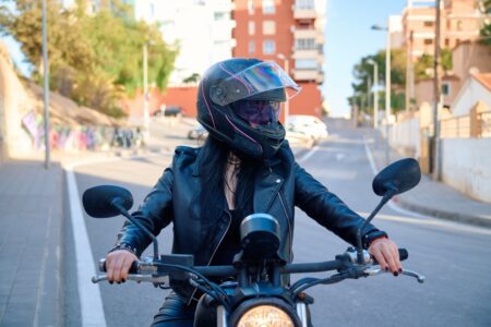 Motorcyclist wearing a full-face helmet and leather jacket on a city street