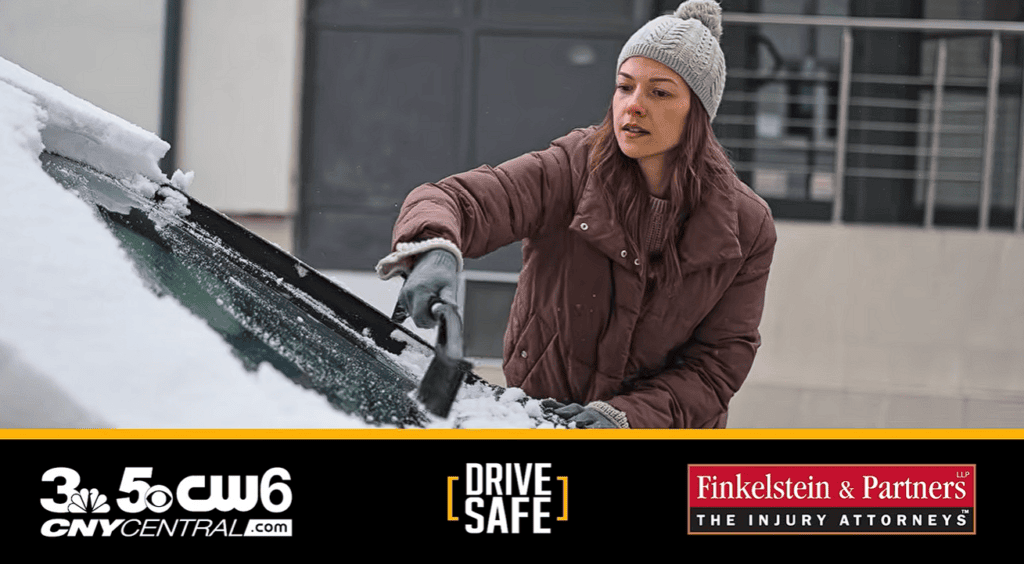 Woman in a knit hat and brown coat scraping snow off a car windshield; logos for CNYCENTRAL.com, DRIVE SAFE, and Finkelstein & Partners The Injury Attorneys